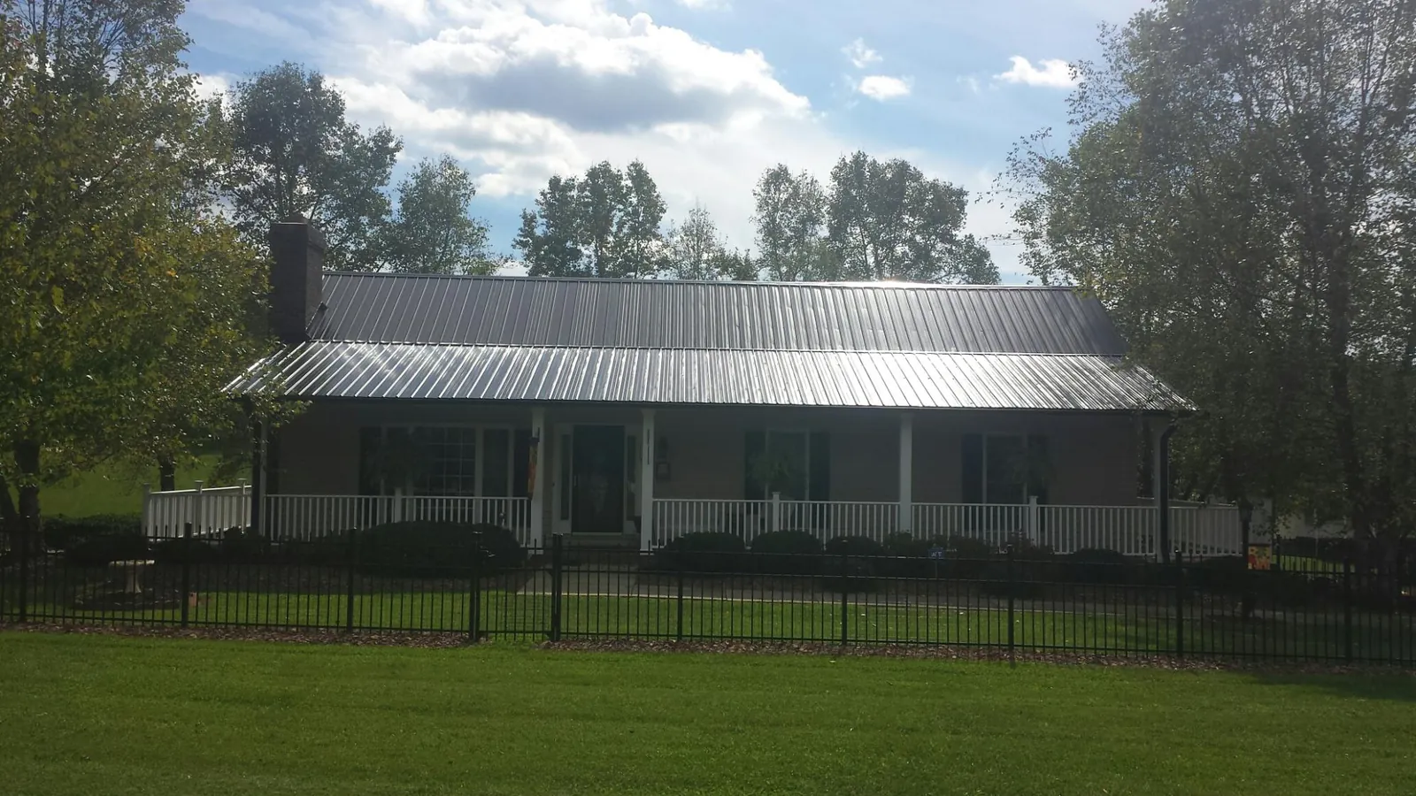 Gray metal roof on a brick ranch with a full width front porch — Gutter Guard Installation work by our crew in Mobile
