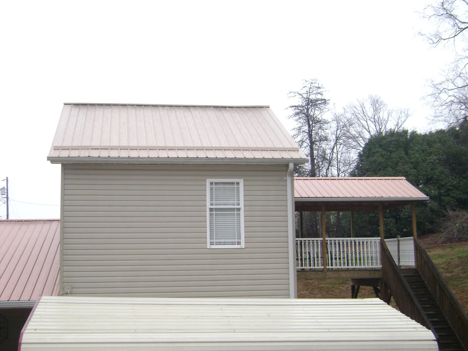 Tan metal roofs on a two story addition and attached porch, from a Roof Replacement job in Mobile